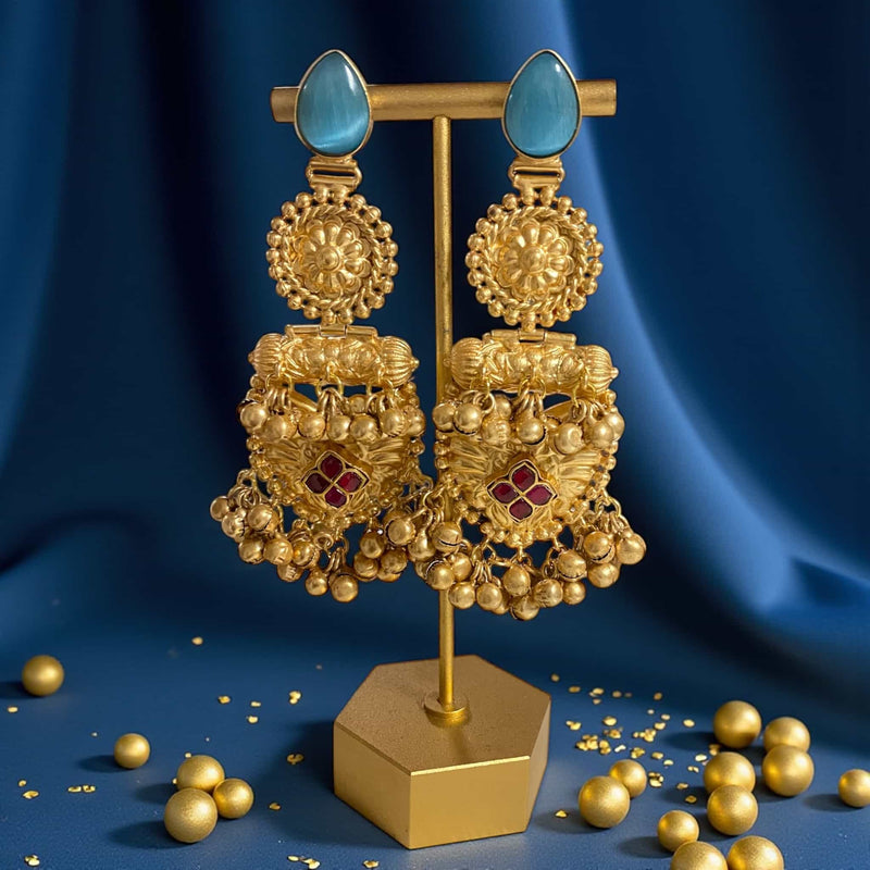 Gold earrings with blue and red stones on a blue background. Antique gold 92.5 silver temple earrings displayed on an elegant earring stand. The earrings feature intricate floral motifs, ruby stones, and traditional ghungroos (bells) that add charm and movement. Captured from a side perspective highlighting the fine detailing, gold plating, and handcrafted design. Perfect for showcasing South Indian temple jewelry style, ideal for weddings, festive occasions, and traditional ethnic looks.