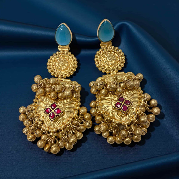Gold earrings with blue and red gemstones on a blue fabric background.  Antique gold 92.5 silver temple earrings with intricate floral design and ruby stones at the center. The earrings feature traditional ghungroos (bells) that add movement and charm. Perfect for South Indian bridal wear, festive occasions, and cultural celebrations. Handcrafted ethnic jewelry with antique gold plating and rich temple-style detailing for an elegant traditional look.