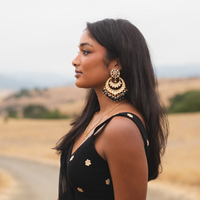 Model wearing Indian Chandbali Earrings with kundan and black beads in gold finish.