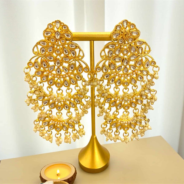 Elegant handcrafted Kundan chandbali earrings in rich gold plating with beautifully arranged pearls, designed to reflect traditional Indian artistry. These earrings highlight fine detailing, shimmering Kundan stones, and graceful pearl hangings that enhance both bridal and festive attire. Ideal for weddings, engagements, Diwali, Eid, Garba nights, and special celebrations, they offer a sophisticated blend of heritage and glamour. A stunning South Asian jewelry piece for women who appreciate high-quality cra