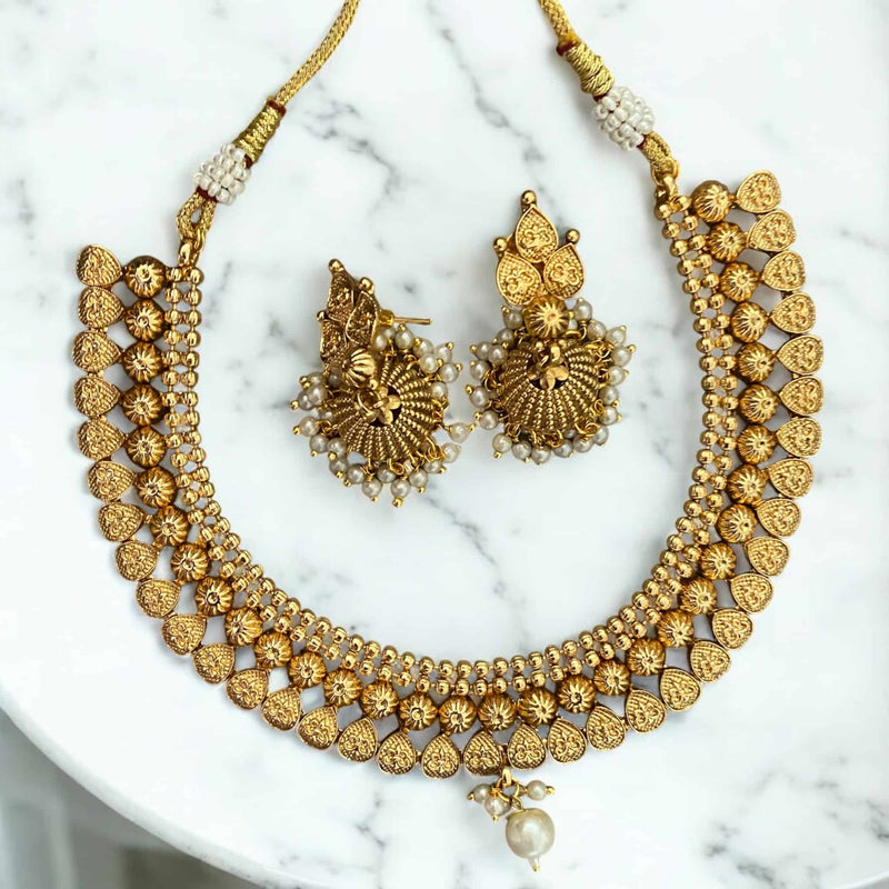 Gold-plated necklace set with pearls and matching jhumka earrings, inspired by traditional Indian jewelry. The intricate necklace design features classic pearl detailing, perfect for bridal wear, weddings, and festive occasions. The coordinated jhumka earrings add elegance and charm, making this set ideal for sarees, lehengas, and ethnic outfits. A timeless South Asian jewelry set that blends heritage craftsmanship with sophistication, perfect for cultural celebrations and special events.