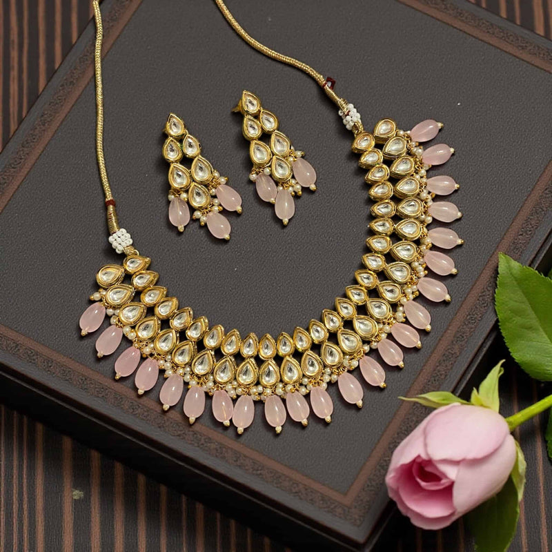 Gold plated Kundan necklace with pink beads displayed on a textured background. Handcrafted Indian jewelry perfect for weddings, parties, and festive outfits. Elegant ethnic necklace designed to match sarees, lehengas, and anarkalis with premium traditional detailing.