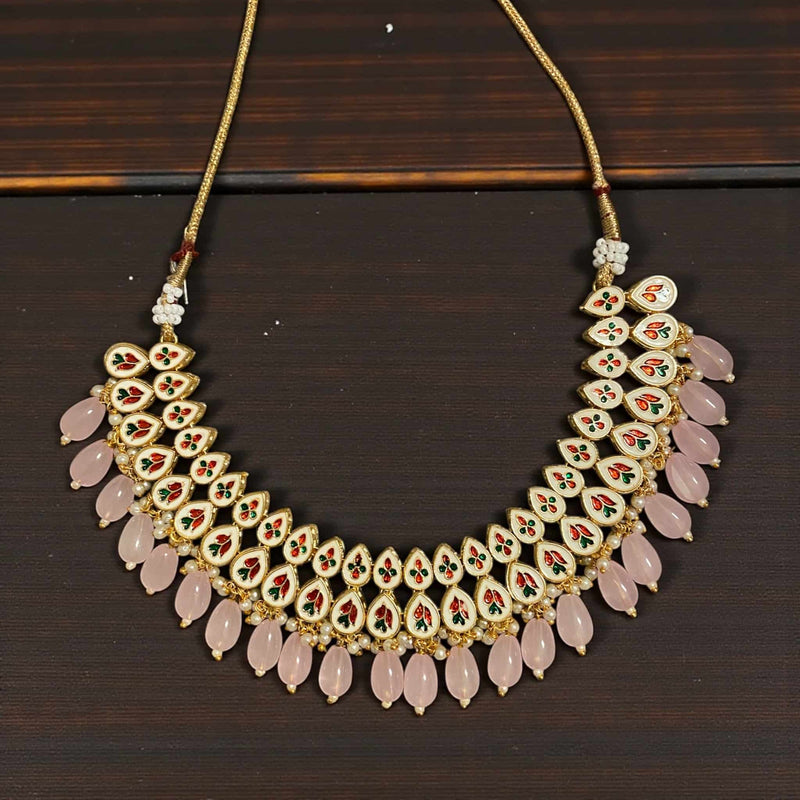 Gold plated Kundan earrings with soft pink bead drops displayed against a green background. Handcrafted traditional Indian jewelry perfect for weddings, parties, and festive outfits. Elegant statement earrings featuring intricate Kundan stones.