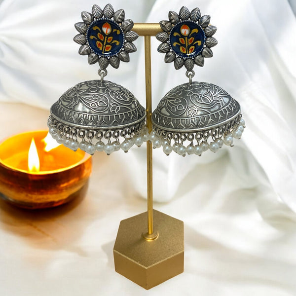 Nami Oxidized Jhumka Earrings with intricate floral design and meenakari work on the stud. Features dome-shaped oxidized silver jhumka with engraved detailing, pearl hangings, and a colorful enamel flower pattern on a dark blue background. Handmade traditional Indian jewelry perfect for ethnic wear, weddings, and festive occasions. A stunning piece of Pakistani jewelry craftsmanship, combining elegance with vintage charm.