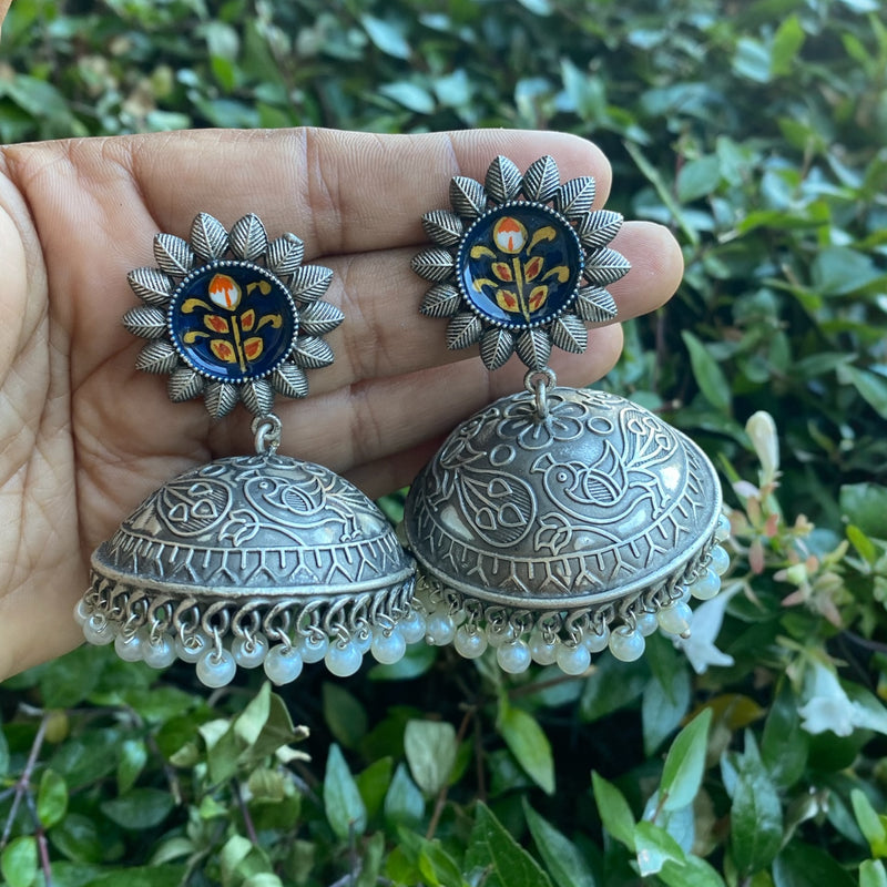Handcrafted Nami Oxidized Jhumka Earrings featuring detailed floral engravings on a dome-shaped jhumka, adorned with pearl drops and a vibrant blue meenakari stud with orange and yellow floral enamel work. A beautiful piece of Indian jewelry with vintage oxidized silver finish, perfect for pairing with sarees or salwar suits. Ideal for traditional wear, festive events, and Pakistani jewelry lovers seeking intricate ethnic earrings.