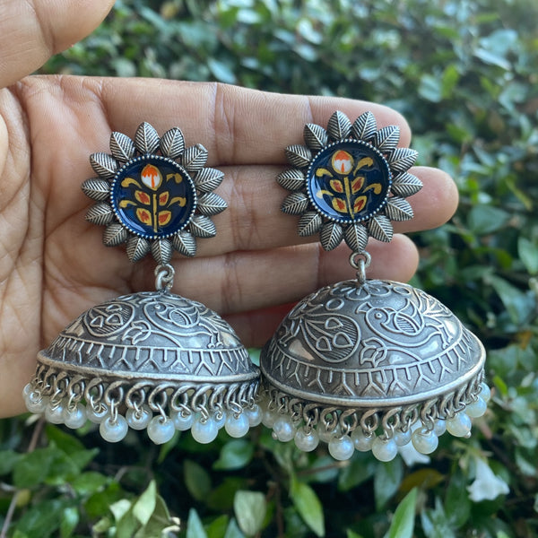 Oxidized silver jhumka earrings with intricate meenakari detailing and pearl hangings. Traditional Indian ethnic jewelry perfect for weddings, festivals, or everyday boho style. Features vintage silver finish, colorful enamel accents, and handcrafted design inspired by South Asian heritage. Ideal for pairing with sarees, lehengas, or fusion outfits.