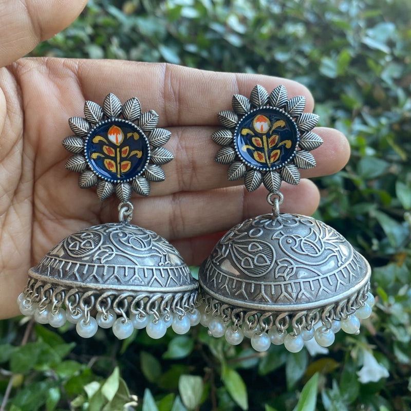 Oxidized silver jhumka earrings with intricate meenakari detailing and pearl hangings. Traditional Indian ethnic jewelry perfect for weddings, festivals, or everyday boho style. Features vintage silver finish, colorful enamel accents, and handcrafted design inspired by South Asian heritage. Ideal for pairing with sarees, lehengas, or fusion outfits.