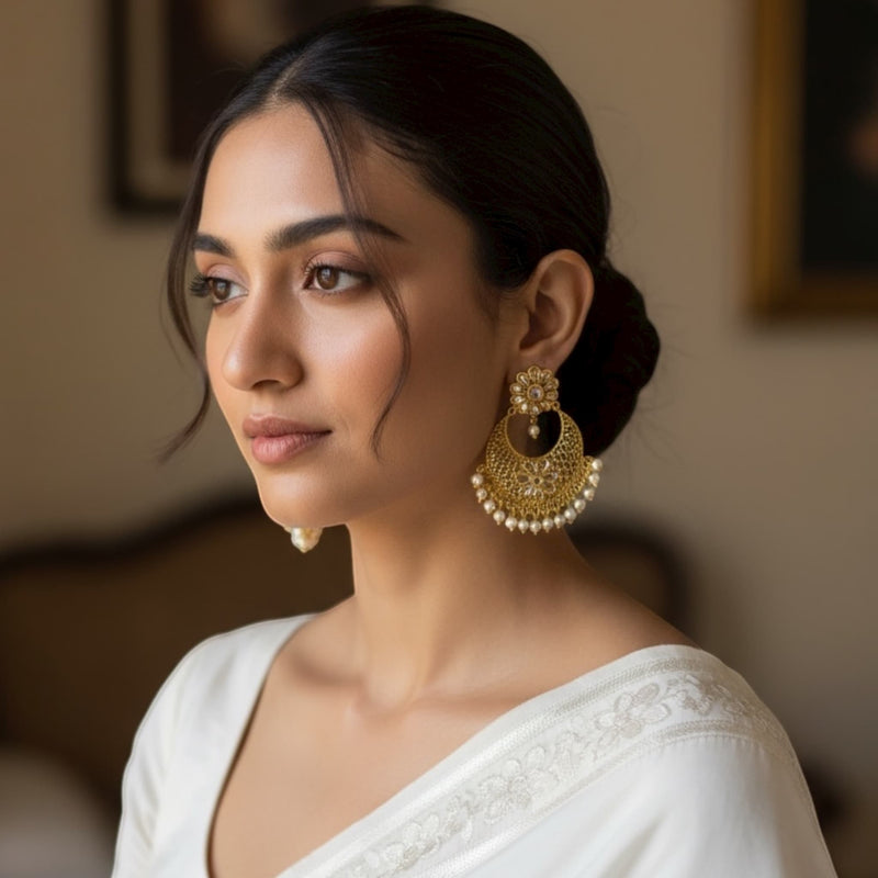 Model wearing Gold Polki Chandbali Earrings with Pearls, highlighting their intricate floral design and sparkling Polki stones. The gold finish and delicate pearl drops enhance the model’s traditional look, pairing perfectly with sarees or lehengas. These earrings radiate elegance and charm, ideal for weddings, festive occasions, and ethnic celebrations, showcasing the timeless beauty of Indian craftsmanship.