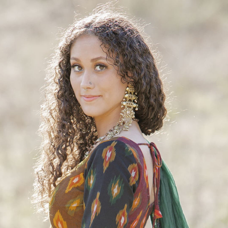 Model wearing long polki earrings with pearl in gold finish.