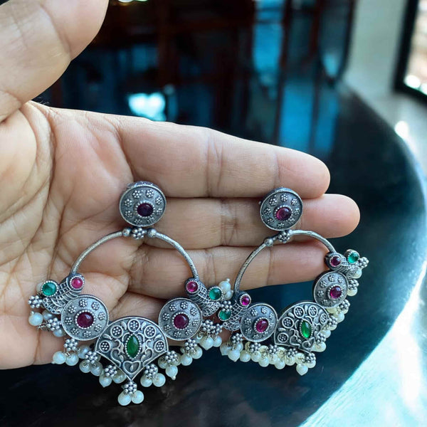 Elegant German silver Chandbali earrings with detailed craftsmanship, adorned with ruby red and green stones and pearl drops. Traditional Indian ethnic jewelry with an oxidized antique finish, perfect for weddings, festive outfits, and bridal wear. South Asian statement earrings for sarees, lehengas, and cultural occasions. Handmade temple-style earrings with classic vintage appeal.