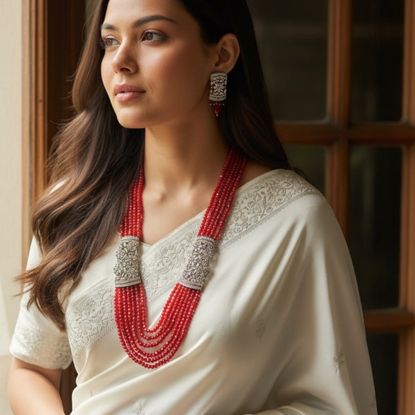 Model wearing the Red Pearl Mahima CZ Long Necklace Set with CZ Flowers | Elegant Indian jewelry featuring deep red pearls and sparkling cubic zirconia floral motifs | Gold-plated long necklace draping gracefully with matching CZ floral earrings | Perfect for weddings, receptions, and festive occasions | Styled with traditional saree or lehenga | Showcasing Romikas Jewelry craftsmanship, combining classic Indian elegance with modern sophistication