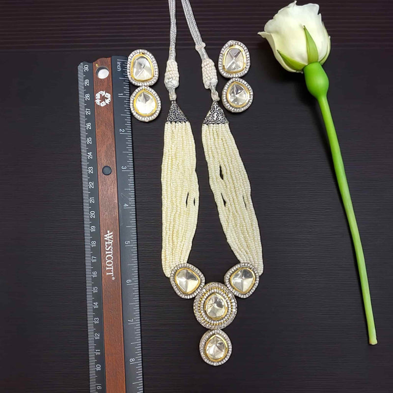 Beaded necklace with crystal accents on a dark surface with a white rose and ruler for scale.