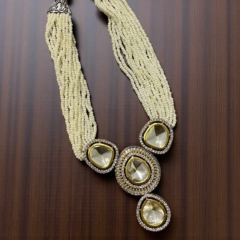 Necklace with multiple strands of beads and large decorative stones on a wooden surface. High-quality Kundan necklace set adorned with silver foil Polki stones, Cubic Zirconia accents, and strands of fine pearls. The statement pendant and matching earrings reflect intricate craftsmanship and regal sophistication. Ideal for weddings, festive events, or cultural celebrations, this handcrafted Indian jewelry set adds a touch of heritage beauty to any bridal or party outfit.

