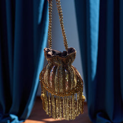 Golden sequin potli bag for women featuring intricate beadwork, shimmer sequins, and elegant tassels. Perfect Indian bridal clutch for weddings, receptions, sangeet, and festive parties. Handmade ethnic handbag with drawstring closure and beaded handle for a luxurious touch. Traditional gold potli purse for brides and bridesmaids, ideal for pairing with sarees, lehengas, and anarkalis. Designer festive potli bag with rich embroidery and sparkling golden details.