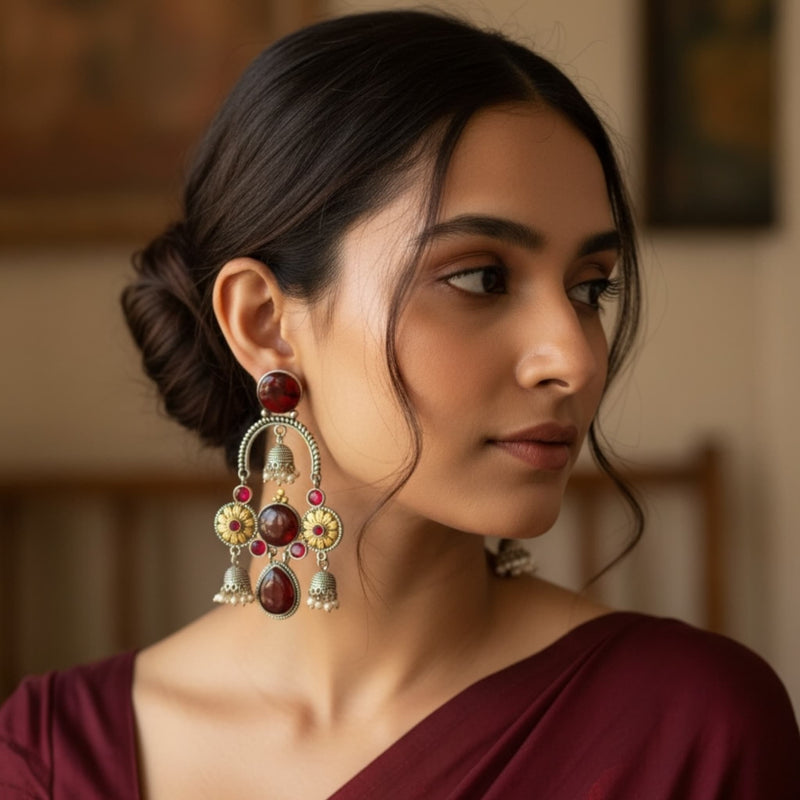 Woman wearing 925 silver-plated ruby chandbali earrings with jhumkas, showcasing intricate floral detailing, ruby stones, and oxidized silver finish. Premium Indian ethnic earrings perfect for weddings, festivals, and party wear.