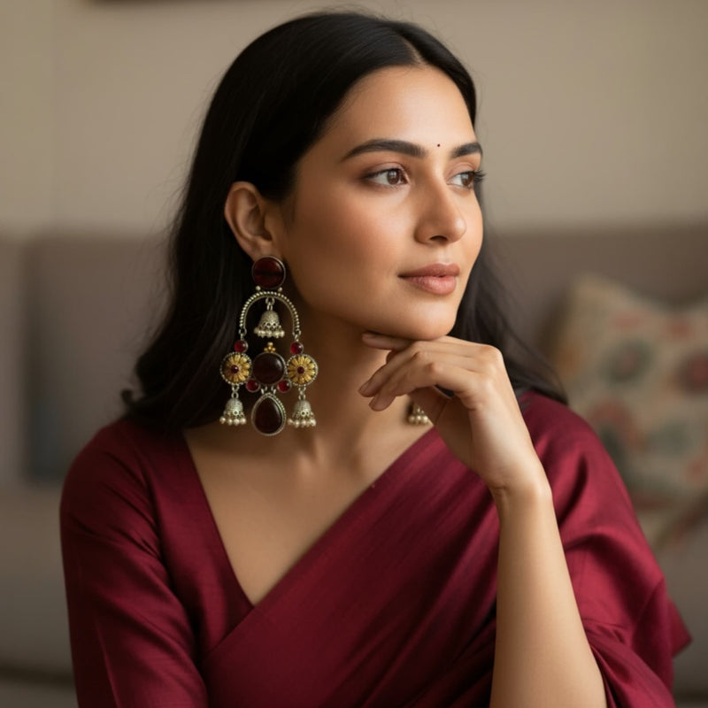 Woman wearing 925 silver-plated ruby chandbali earrings with jhumkas, showcasing intricate floral designs, shimmering ruby stones, and oxidized silver detailing. These handcrafted Indian ethnic earrings feature elegant jhumka drops, perfect for weddings, festivals, parties, and traditional outfits. Clear model display highlights size, shine, craftsmanship, and luxurious statement style