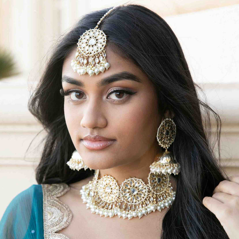 Model wearing Indian traditional kundan choker set with jhumk and maang tikka.