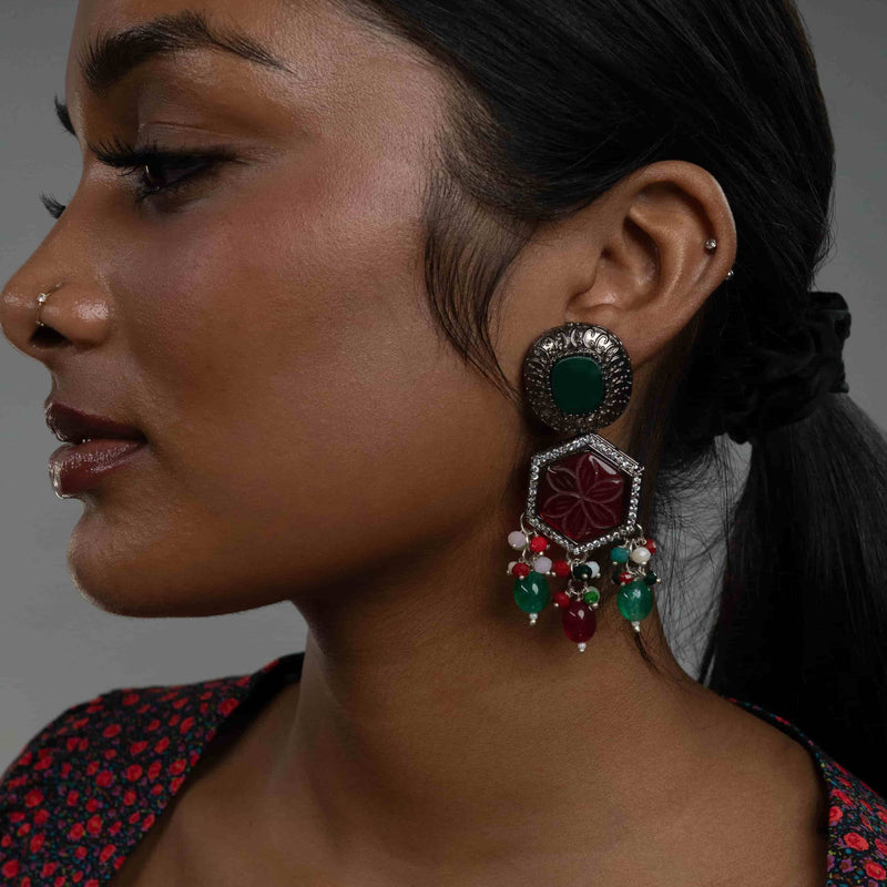 Model wearing Indian Earrings in black polish featuring ruby carved stone and green stone from Indian Jewelry Online Store.