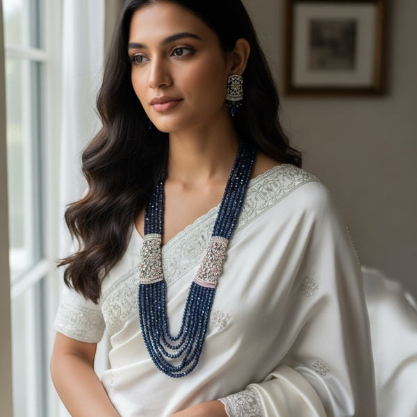 Model wearing the Blue Pearl Mahima CZ Long Necklace Set with CZ Flowers | Elegant Indian jewelry featuring blue pearls and sparkling cubic zirconia flowers | Gold-plated long necklace draping gracefully | Matching CZ floral earrings | Styled with traditional saree or lehenga | Perfect for weddings, festive occasions, and special celebrations | Showcasing Romikas Jewelry craftsmanship, combining classic Indian elegance with modern sophistication | Statement bridal jewelry set highlighting color, design, and