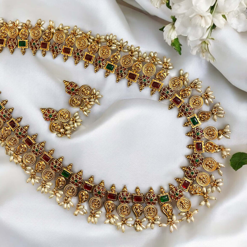 Antique gold long mala necklace featuring ruby and green stones with pearls, designed in traditional South Indian temple jewelry style. A perfect ethnic bridal and festive accessory with intricate gold detailing for a regal and timeless look.