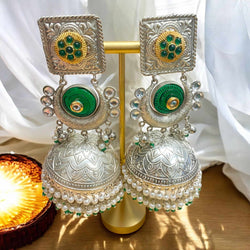 Green 92.5 silver-coated jhumka earrings with intricate silver detailing and delicate pearl drops. Handcrafted traditional Indian jewelry designed for weddings, festive occasions, and cultural celebrations. The rich green enamel and elegant silver work make these earrings the perfect statement piece to complement sarees, lehengas, and ethnic wear. A timeless accessory for brides and fashion lovers seeking an elegant ethnic look.
