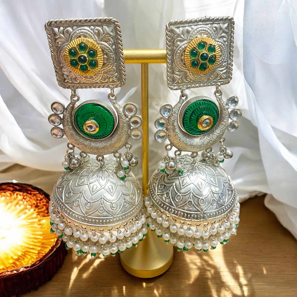 Green 92.5 silver-coated jhumka earrings with intricate silver detailing and delicate pearl drops. Handcrafted traditional Indian jewelry designed for weddings, festive occasions, and cultural celebrations. The rich green enamel and elegant silver work make these earrings the perfect statement piece to complement sarees, lehengas, and ethnic wear. A timeless accessory for brides and fashion lovers seeking an elegant ethnic look.
