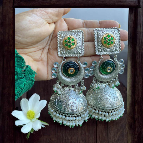 Elegant green 92.5 silver-coated jhumka earrings with pearl drops, showcasing intricate silver craftsmanship and vibrant green enamel. Perfect for weddings, festivals, and special occasions. These traditional Indian earrings add a touch of sophistication to any outfit, from sarees and lehengas to Indo-western styles. The combination of delicate pearls and rich green color makes these jhumkas an exquisite choice for ethnic jewelry lovers.