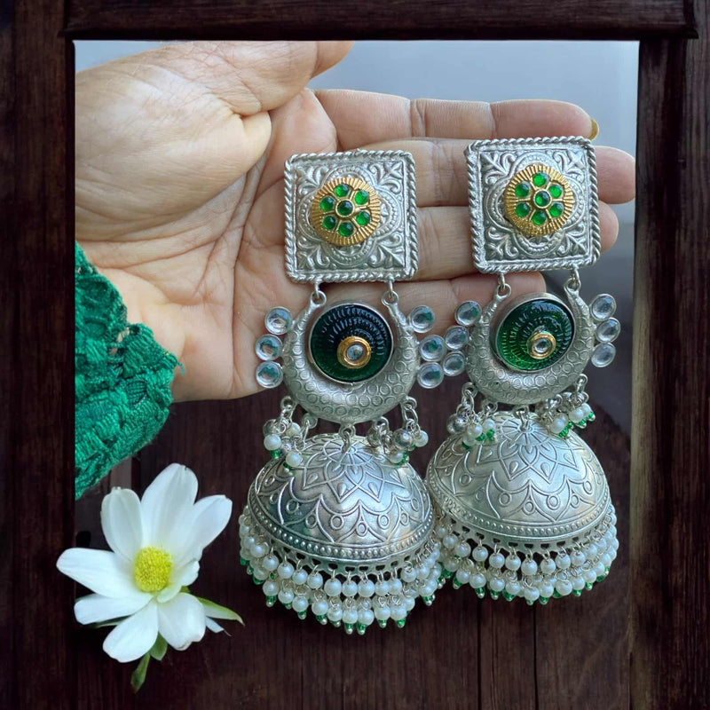 Elegant green 92.5 silver-coated jhumka earrings with pearl drops, showcasing intricate silver craftsmanship and vibrant green enamel. Perfect for weddings, festivals, and special occasions. These traditional Indian earrings add a touch of sophistication to any outfit, from sarees and lehengas to Indo-western styles. The combination of delicate pearls and rich green color makes these jhumkas an exquisite choice for ethnic jewelry lovers.