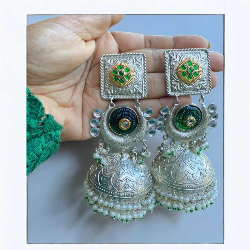 Handcrafted green 92.5 silver-coated jhumka earrings with pearl accents, featuring intricate silver detailing and vibrant green enamel. These traditional Indian earrings are perfect for weddings, festivals, and festive celebrations. The elegant pearl drops and rich green hue make these jhumkas an ideal accessory to complement ethnic attire like sarees, lehengas, and salwar suits. A timeless and sophisticated addition to any jewelry collection.