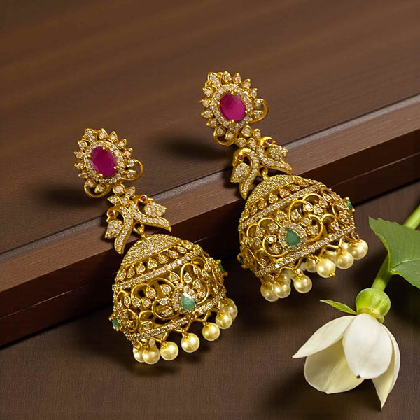 Gold CZ jhumka earrings with ruby stone studs, emerald accents, and pearl hangings. High-quality gold-plated Indian earrings with detailed filigree and sparkling cubic zirconia. Perfect accessory for weddings, festivals, parties, and traditional outfits like sarees and lehengas.