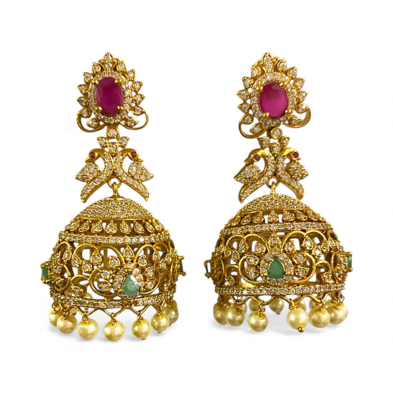 Indian gold CZ jhumka earrings decorated with ruby tops, emerald motifs, and shimmering CZ work. Finished with classic pearl danglings for a luxurious touch. Great for weddings, celebrations, and South Asian outfits.
