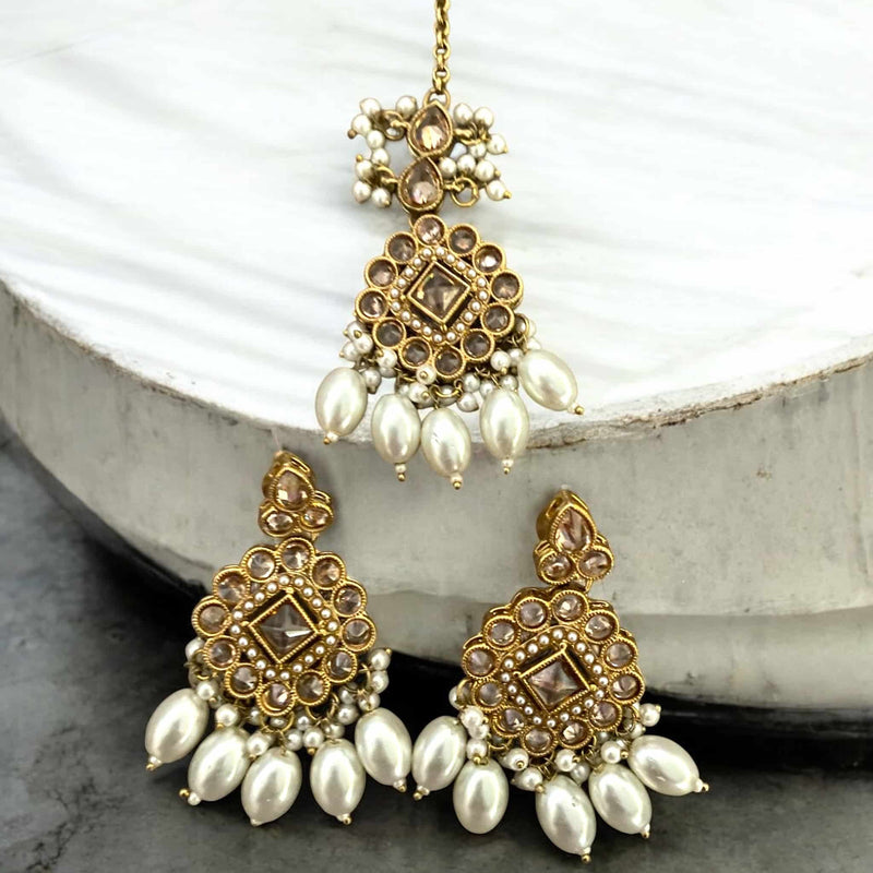 Matching Polki earrings and maang tikka set with pearls, featuring intricate Kundan Polki work and a traditional gold-plated finish. Perfect for Indian bridal wear and South Asian weddings, this handcrafted set adds elegance and charm to any festive or ethnic outfit. The earrings and forehead accessory are adorned with pearl detailing, ideal for Desi brides seeking luxurious, high-end jewelry for their special day.