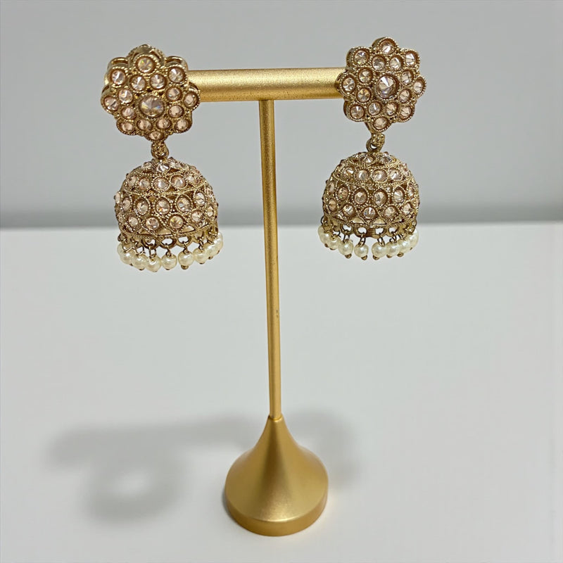 Antique mehndi gold Polki jhumka earrings with pearl drops displayed on a gold stand against a clean white background. The earrings feature floral Polki studs and intricately detailed dome-shaped jhumkas with small pearl hangings, showcasing the craftsmanship, sparkle, and traditional design of the jewelry.