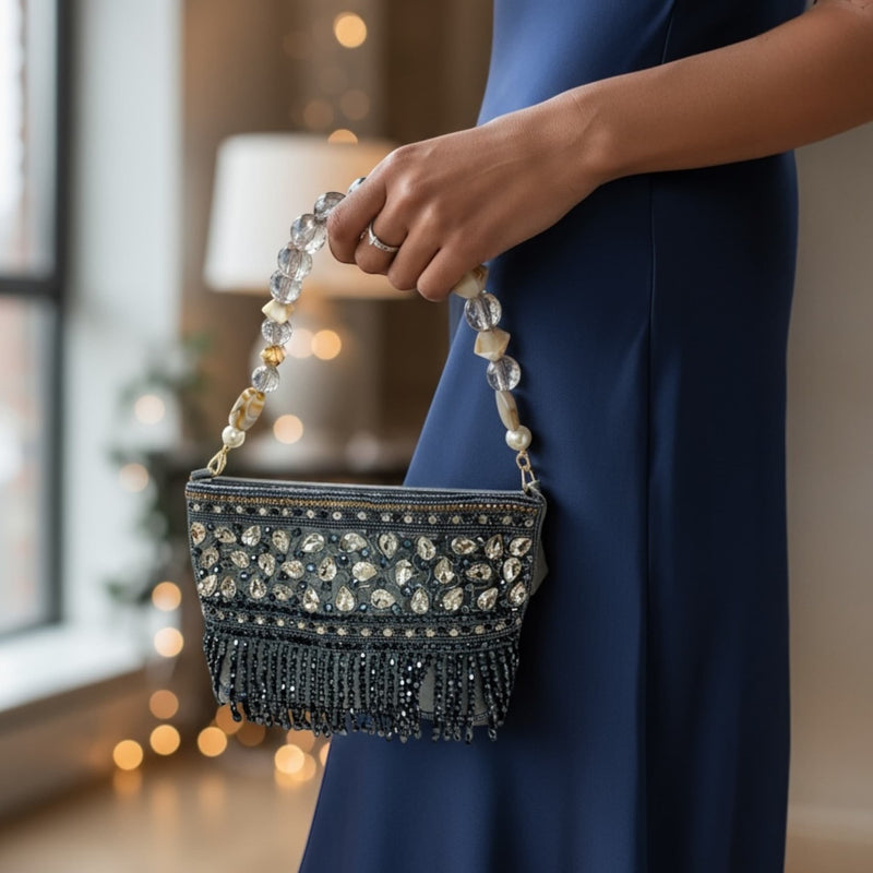 Elegant woman holding a grey beaded purse with sparkling stone work and crystal handle from Romikas Jewelry Shop. Handmade Indian clutch designed for weddings, parties, and festive occasions. Perfect accessory to complement sarees, lehengas, and evening gowns with timeless elegance.