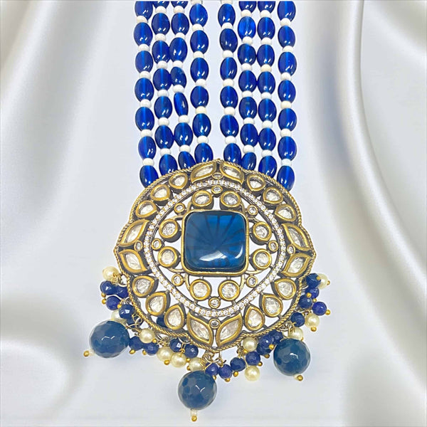 The pendant of this Royal Blue Kundan Necklace Set features intricate craftsmanship with a stunning combination of Polki stones, blue Monalisa accents, and detailed Kundan work. Set in a gold-plated base with silver foil back meenakari, the pendant radiates a royal charm and brilliance. Surrounded by delicate pearls and hanging blue beads, it exudes elegance and sophistication—perfect for brides and festive wear, adding a regal focal point to any traditional Indian outfit.