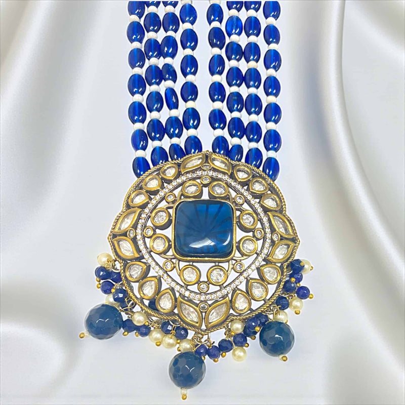 The pendant of this Royal Blue Kundan Necklace Set features intricate craftsmanship with a stunning combination of Polki stones, blue Monalisa accents, and detailed Kundan work. Set in a gold-plated base with silver foil back meenakari, the pendant radiates a royal charm and brilliance. Surrounded by delicate pearls and hanging blue beads, it exudes elegance and sophistication—perfect for brides and festive wear, adding a regal focal point to any traditional Indian outfit.